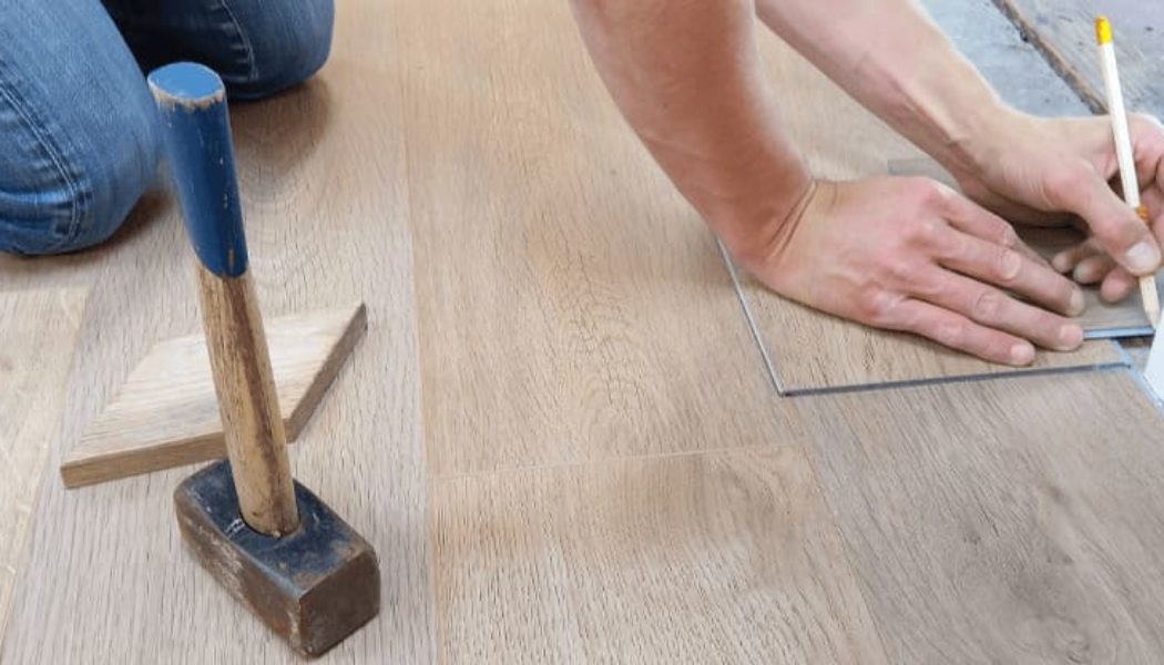 man installing luxury vinyl plank floors in doorway