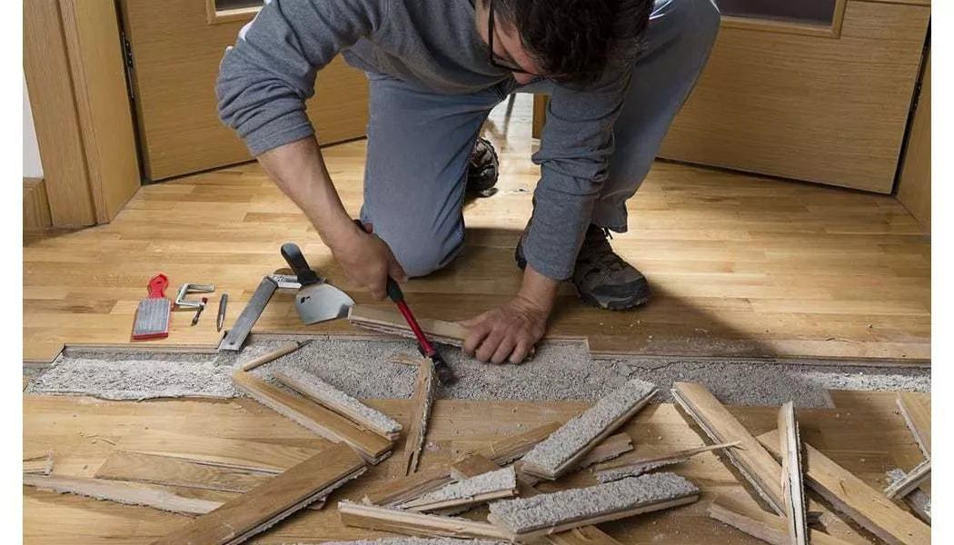 man working on damaged hardwood in his home