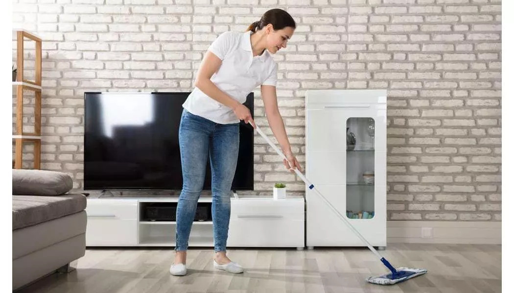 woman using a soft mop on her gray hardwood floors